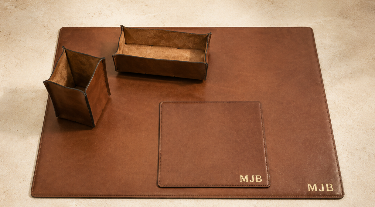 Personalized Korchmar leather desk set with gold MJB monograms on a warm stone surface