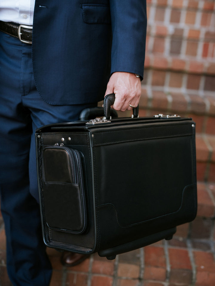 Black Person in a suit holding a black suitcase catalog case lawyer case on a brick pavement