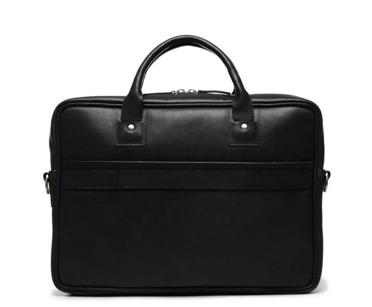 Black Full grain mill dyed American saddle leather Solid brass hardware in matte nickel finish Solid brass polished tooth zipper Removable, adjustable shoulder strap with ergonomic pad Front zippered and slim literature pocket on the back Removable, snap-in key chain Padded interior computer pocket Fully lined with signature 6.4 oz yarn dyed twill Carry bag strap slide over telescoping luggage handle Handcrafted with care in our own factory Fits most 13" laptops Dimensions: 14.5" x 2.5" x 11"