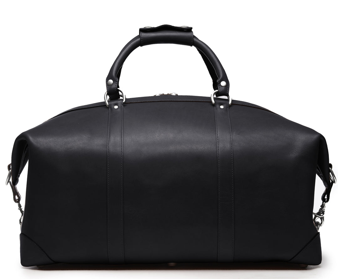 Black Full grain American leather finished with natural oils and waxes Solid nickel antiqued hardware Clamp down ends allow for expansion and increased interior capacity Fully lined with signature 6.4 oz yarn dyed twill Interior zippered pockets Removable, adjustable shoulder strap with ergonomic pad Customizable monogram patch on exterior Handcrafted with care in our own factory Dimensions: 22" x 10" x 14" #color_black