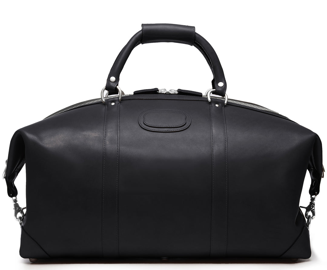 Black 22" Leather Weekender  The Twain weekender in Korchmar's Classic Leather is made of American cowhide leather that is selected from the top 5% of available hides. Colored only with aniline dyes, this leather retains its natural beauty over time and features visible markings that are characteristic of only the finest leather. One of our best-selling weekender styles, the Twain is ideal for leisure or business travel. #color_black