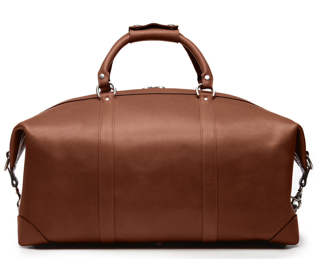 Brown Full grain American leather finished with natural oils and waxes Solid nickel antiqued hardware Clamp down ends allow for expansion and increased interior capacity Fully lined with signature 6.4 oz yarn dyed twill Interior zippered pockets Removable, adjustable shoulder strap with ergonomic pad Customizable monogram patch on exterior Handcrafted with care in our own factory Dimensions: 22" x 10" x 14" #color_brown