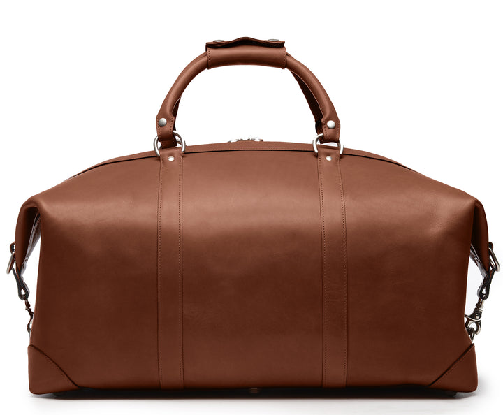 Brown Full grain American leather finished with natural oils and waxes Solid nickel antiqued hardware Clamp down ends allow for expansion and increased interior capacity Fully lined with signature 6.4 oz yarn dyed twill Interior zippered pockets Removable, adjustable shoulder strap with ergonomic pad Customizable monogram patch on exterior Handcrafted with care in our own factory Dimensions: 22" x 10" x 14" #color_brown