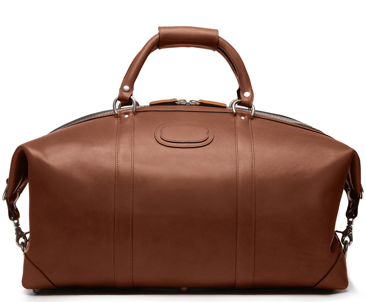 Brown 22" Leather Weekender  The Twain weekender in Korchmar's Classic Leather is made of American cowhide leather that is selected from the top 5% of available hides. Colored only with aniline dyes, this leather retains its natural beauty over time and features visible markings that are characteristic of only the finest leather. One of our best-selling weekender styles, the Twain is ideal for leisure or business travel.