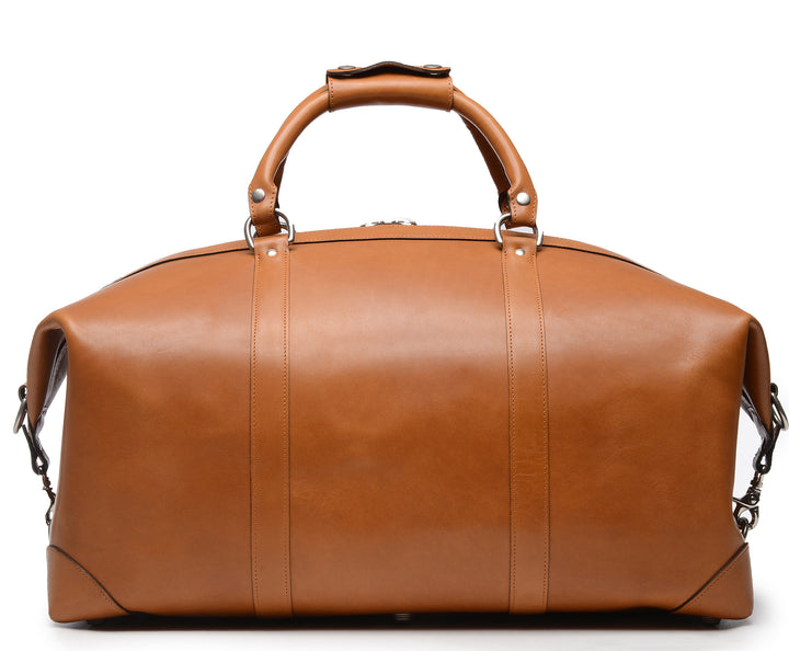 Tan Full grain American leather finished with natural oils and waxes Solid nickel antiqued hardware Clamp down ends allow for expansion and increased interior capacity Fully lined with signature 6.4 oz yarn dyed twill Interior zippered pockets Removable, adjustable shoulder strap with ergonomic pad Customizable monogram patch on exterior Handcrafted with care in our own factory Dimensions: 22" x 10" x 14" #color_tan