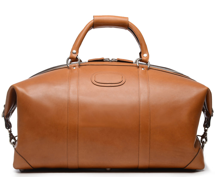 Tan 22" Leather Weekender  The Twain weekender in Korchmar's Classic Leather is made of American cowhide leather that is selected from the top 5% of available hides. Colored only with aniline dyes, this leather retains its natural beauty over time and features visible markings that are characteristic of only the finest leather. One of our best-selling weekender styles, the Twain is ideal for leisure or business travel. #color_tan