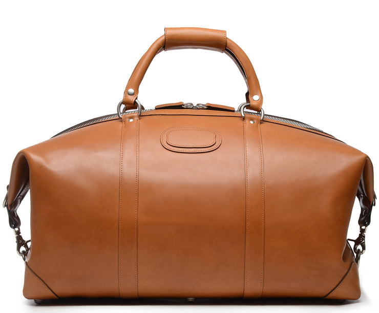 Tan 22" Leather Weekender  The Twain weekender in Korchmar's Classic Leather is made of American cowhide leather that is selected from the top 5% of available hides. Colored only with aniline dyes, this leather retains its natural beauty over time and features visible markings that are characteristic of only the finest leather. One of our best-selling weekender styles, the Twain is ideal for leisure or business travel.