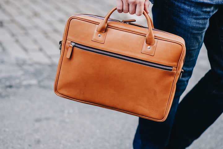 Full-grain mill dyed American saddle leather Solid brass hardware in matte nickel finish Solid brass polished tooth zipper Removable, adjustable shoulder strap with ergonomic pad #color_tan