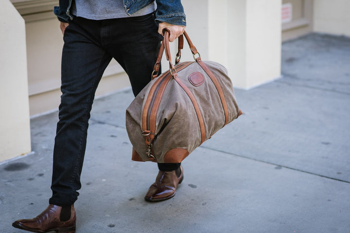 The waxed canvas Flynn is ideal for leisure or business travel. At 20", it is designed to fit comfortably in overhead compartments. The Flynn waxed canvas duffel bag is handcrafted with water-resistant waxed canvas and includes a removable, adjustable leather shoulder strap. #color_olive