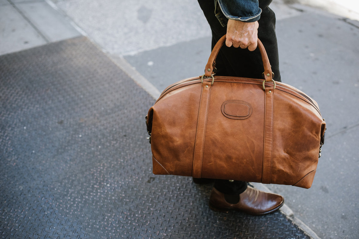 Full grain American leather finished with natural oils and waxes Solid brass antiqued hardware Clamp down ends allow for expansion and increased interior capacity Fully lined with signature 6.4 oz yarn dyed twill