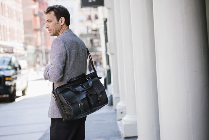 Full grain American pebbled leather trimmed with oil tanned saddle leather Spacious interior single gusset Built-in 15" laptop sleeve Zippered interior pocket Multiple expandable leather organizer pockets #color_black